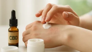 CBD w pielęgnacji skóry – dłonie, krem i olejek na tle naturalnego światła.
